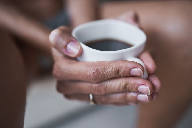 Faceless woman holding ceramic cup with coffee