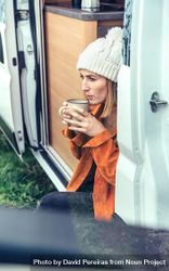 Female relaxing with coffee sitting on camper van step, close up vertical 4mr1db