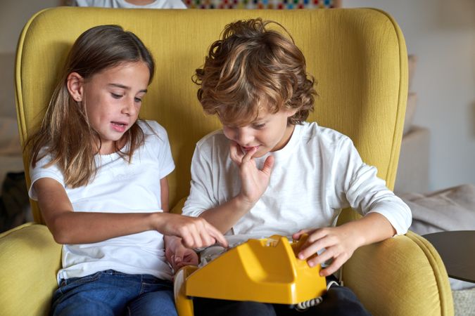 Siblings dialing number on old fashioned telephone