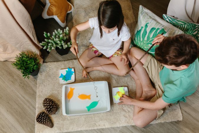Unrecognizable children playing fishing game at home