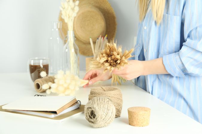 Woman in blue striped shirt crafting a dried floral arrangement