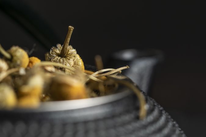 Spoonful of dried chamomile on brass teapot