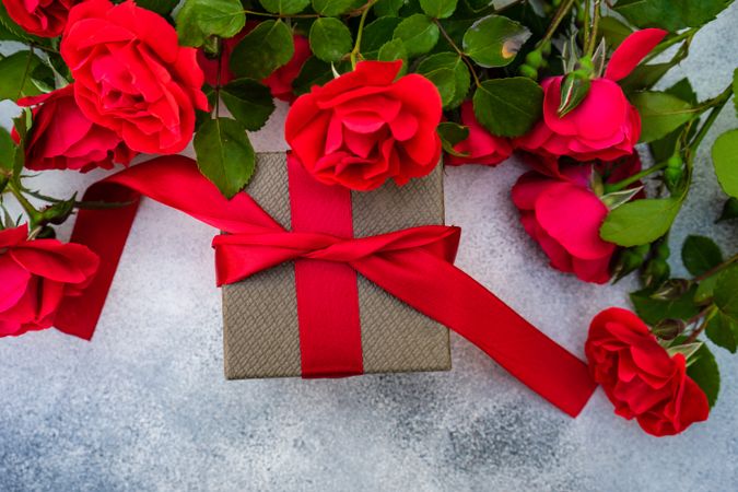 Top view of red roses with small gift box with red ribbon