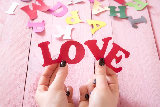 Hands holding paper letters that form the word love
