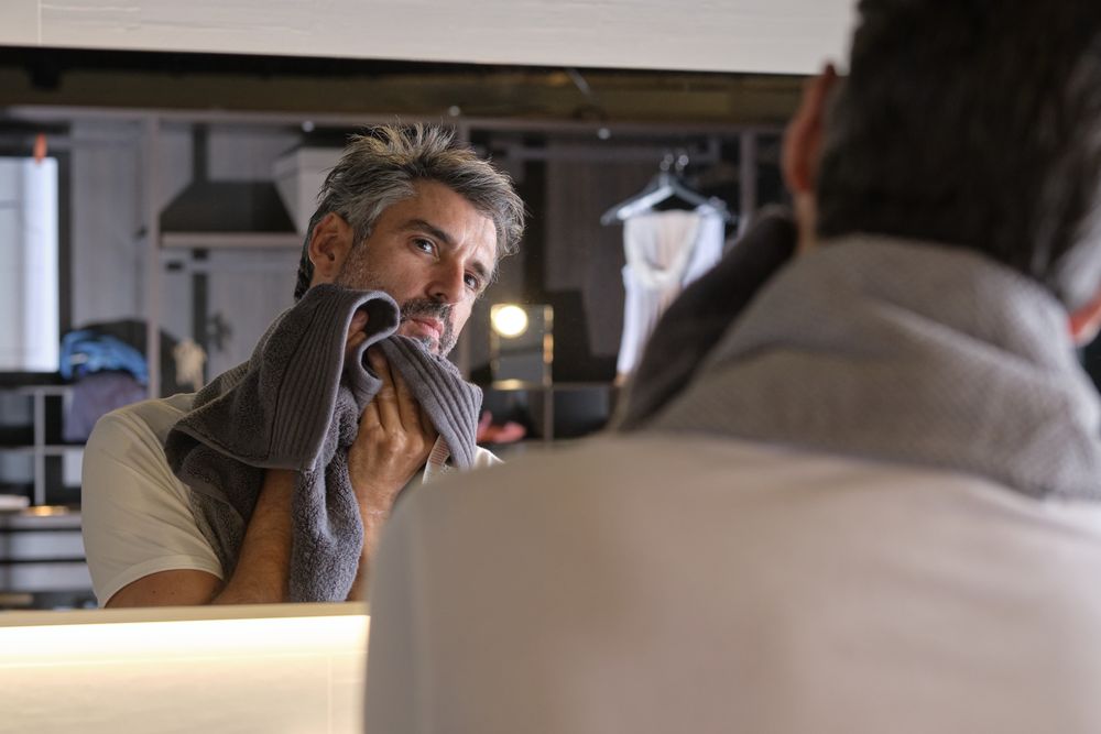 Adult man wiping face with towel