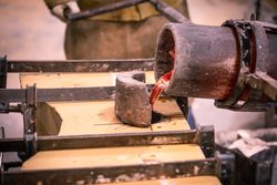 Man pouring heated metal from crucible in form