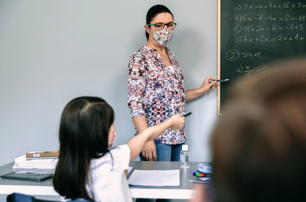 Teacher with mask explaining exercises in math class