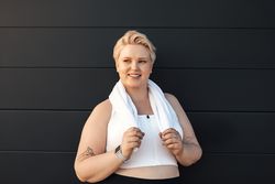 Smiling blonde woman in workout gear with towel around her neck
