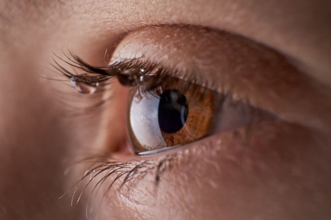 Eye of unrecognizable discontent kid with tears