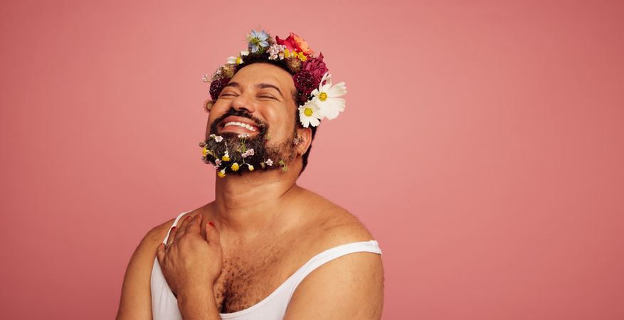 Man with decorative flower beard smiling on pink background