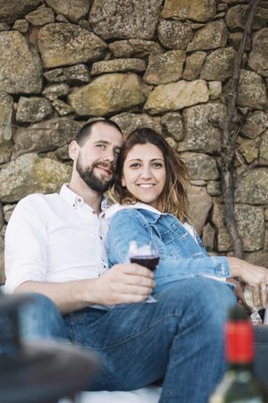 Relaxed couple sitting on a terrace while bonding and enjoying a cup of wine