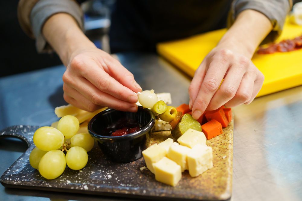 Person plating a cheese board