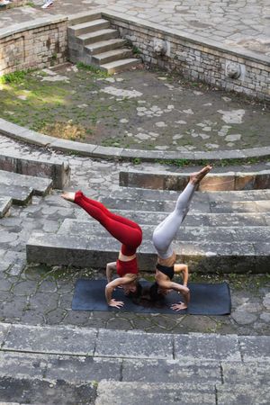 Slender women practicing yoga in headstand on mat