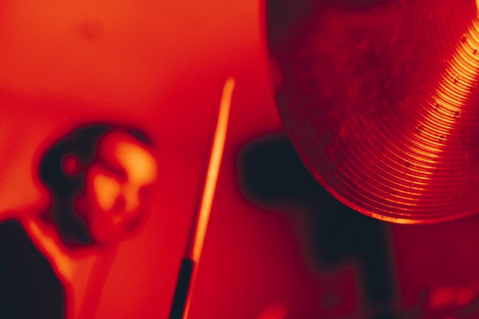 Man with drumsticks playing on drums in redness