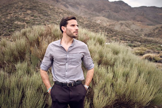 Confident man standing in valley covered with savanna grass