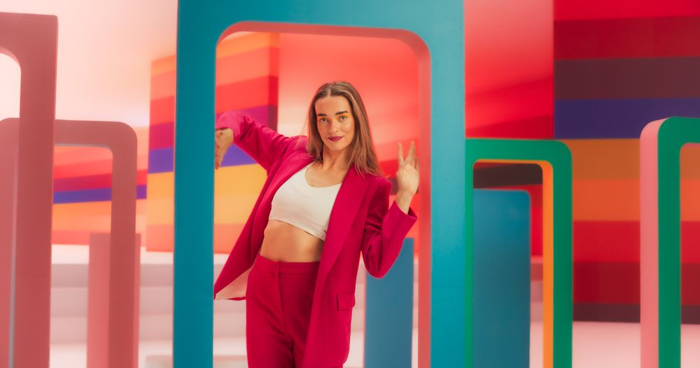 Portrait of Talented Energetic Woman Dancing with Hypnotic Hand Movement While Looking at the Camera: Stylish Female Dancer Performing a Modern Choreography in a Studio with Colorful Funky Background