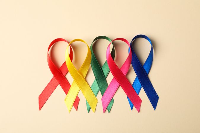 Flat lay composition with awareness ribbons on color background, space for text.