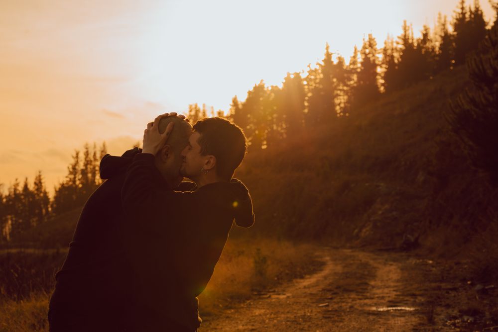 Men hugging and kissing in forest