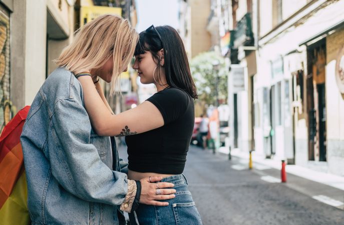 Lesbian couple with LGBT flag standing on street