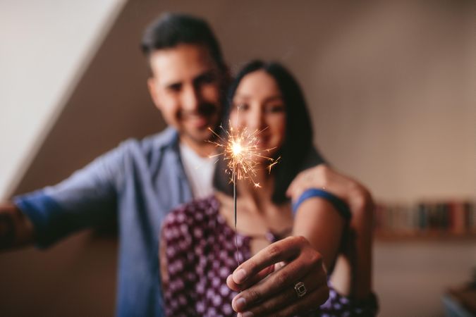 Young couple celebrating with sparkler indoors