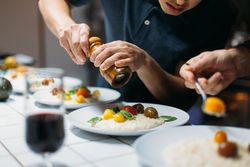 Man grinding pepper on risotto