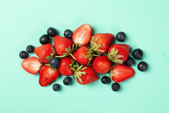 Tasty red strawberry and blueberry on mint background, top view