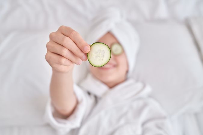 Boy demonstrating cucumber slice and relaxing at home