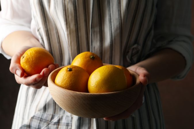Woman holds bowl with lemons. Ripe fruit