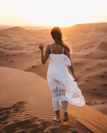 Woman in white dress walking in desert
