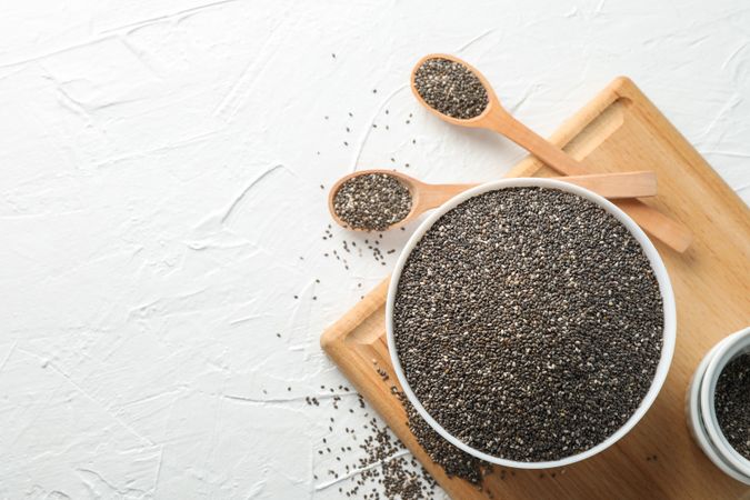 Bowl and spoons with chia on blank background, top view