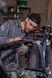 Serious male mechanic fixing motorbike in garage
