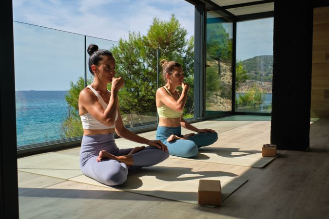 Women breathing deeply while sitting in Lotus pose