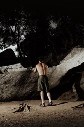 Man practicing rock climbing among large rocks in a forest