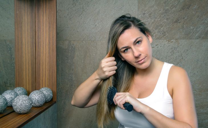 young woman straightening hair with a straightener