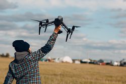 Back view of man in plaid shirt holding a drone 4dDZA4