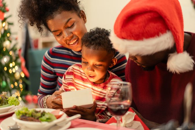 Black family support their son to open a glowing gift box on Christmas season