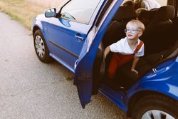 Happy little child in blue car park on asphalt road in countryside