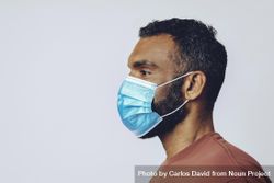 Profile of male looking away from camera wearing medical face mask in studio shoot, copy space 48YqJb