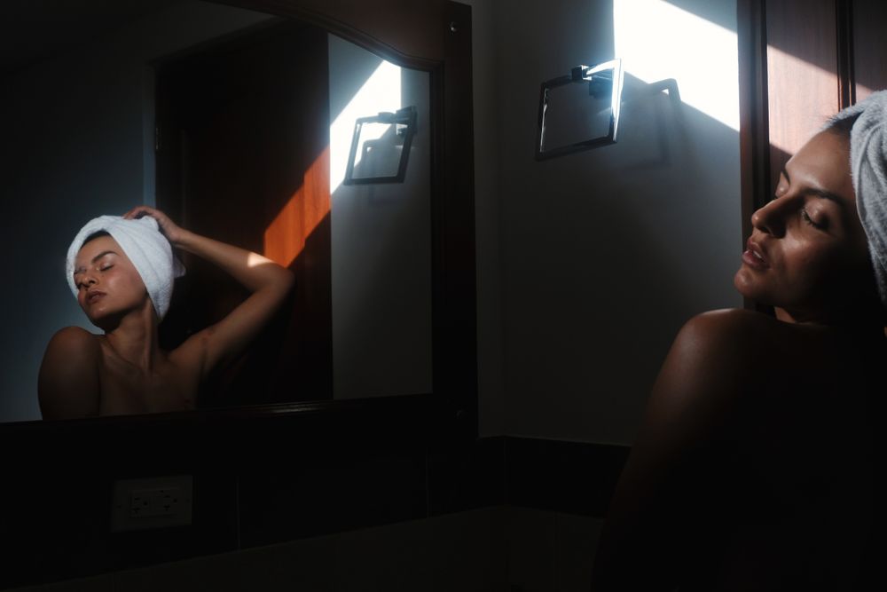 woman with towel on head against mirror in bathroom