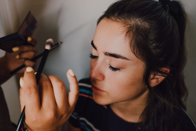 Young woman getting makeup by makeup artist in salon