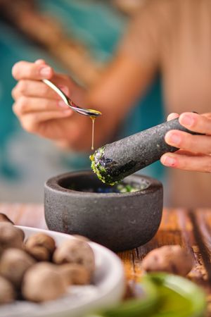Unrecognizable female adding oil to sauce