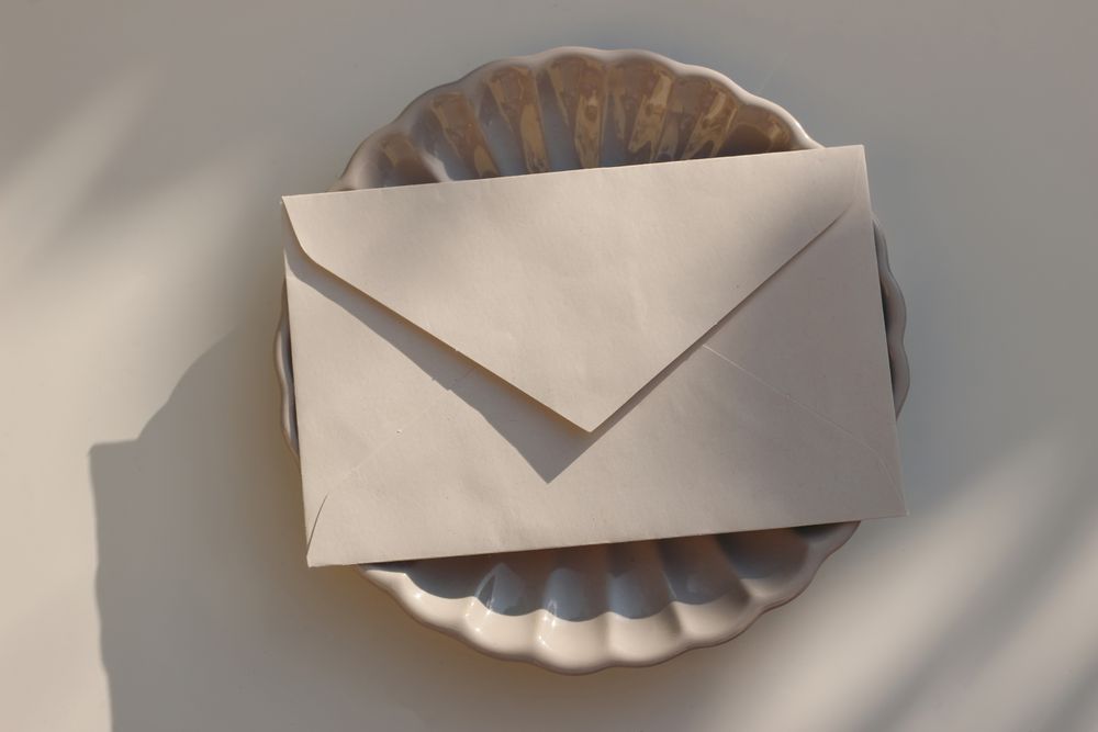 Closed beige envelope on plate with shadows