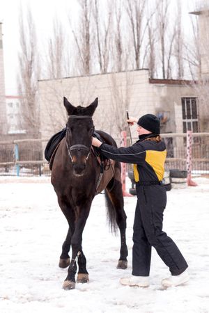 Person leading a lively horse in snow. Dressage.