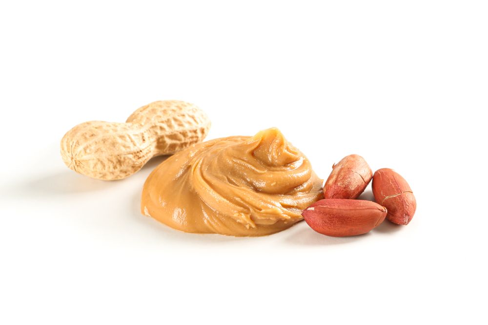 Creamy peanut butter and peanut isolated on light background. A traditional product of American cuisine