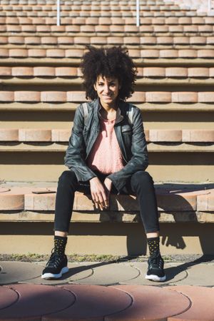 Woman with afro hair sitting on the steps of a stadium