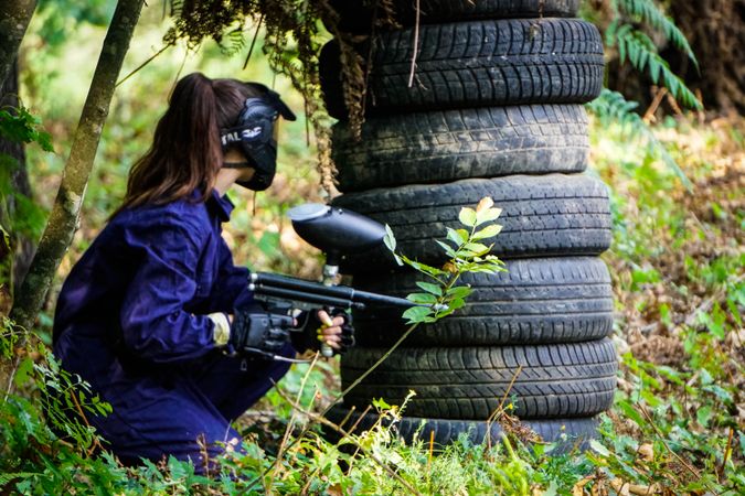 Woman in blue jacket holding dark paintball rifle