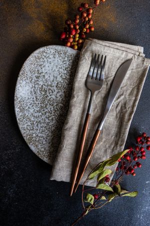 Autumnal napkin, silverware and grey plate with wild red berries