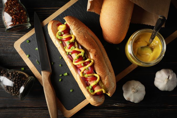 Tasty hot dog and ingredients on wooden background