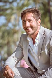 Cheerful man in suit sitting in park