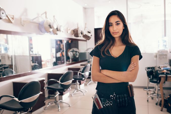 Woman standing with arms crossed in hair salon